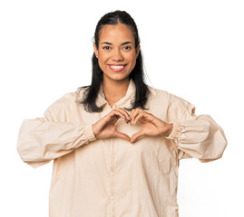 Young Filipina woman smiling and showing a heart shape with hands.