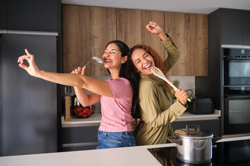 Friends singing and cooking together happily in modern kitchen