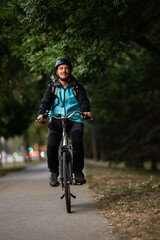 Delivery man riding electric bicycle in city park