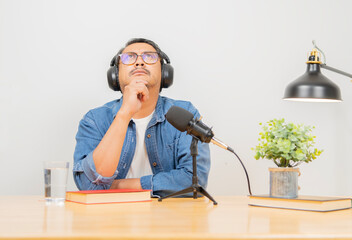Bearded man podcaster looking up while thinking with headphones