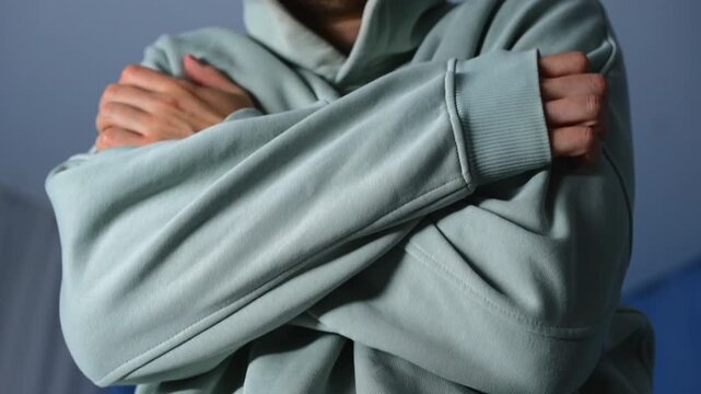 A man in a blue sweater warms himself with his hands in a cool room.
No heating in the house and home heating.
Cold, warmth, body, thermoregulation, ventilation
