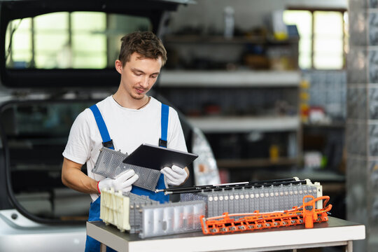 Serviceman testing electric vehicle battery pack in workshop