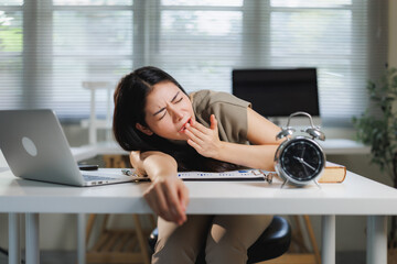 Tired woman yawning while working at desk