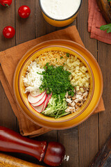 Cold summer russian soup okroshka with kefir on wooden decorated background
