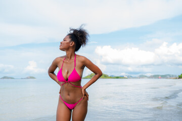 Beautiful African american woman in pink bikini on tropical beach. Portrait of dark skinned woman...