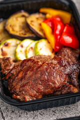 Grilled beef with vegetables in black takeaway container
