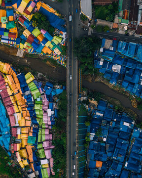 Aerial view of a vibrant rainbow of colors contrasting with deep blues, divided by a road and river, creating a stunning urban tapestry, Malang, Malang, Indonesia.