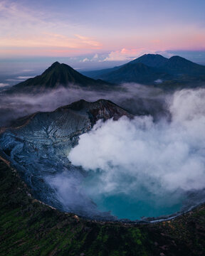 Aerial view of the ethereal Ijen volcano, where turquoise waters meet plumes of sulfurous smoke beneath a pastel sky, Mt. Ijen, Jawa Timur, Indonesia.