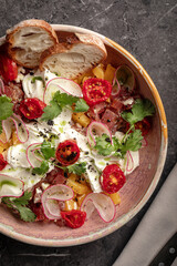 Colorful vegetable salad with radish, cherry tomatoes and bread slices