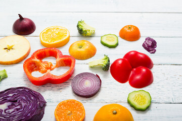 sliced fruit and vegetable circles on white wood table