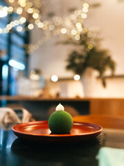 Rich green mousse dessert looking like christmas tree ball on a big plate in cafeteria