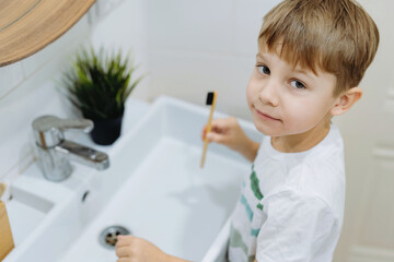 cute 6 years old boy washing his face over the sink in bathroom. Image with selective focus
