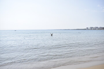 Obraz premium view of the sea, the horizon and a man in the distance with his hands raised from the shore