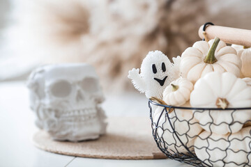 Halloween celebration. White skull, ghost, and pumpkins on the table. Banner, background for Halloween or Day of the Dead.