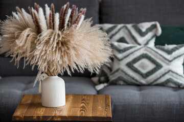 A cozy home-made autumn composition. Still life. A beautiful bouquet of dried pampas grass in a vase on a table in the living room.