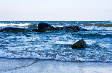 Crashing Ocean Waves Against Mossy Rocks on Clear Day