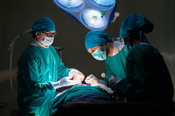 Group of concentrated surgical doctor team doing surgery patients in hospital operating theater. Professional medical team doing critical operations.