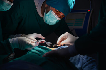 Group of concentrated surgical doctor team doing surgery patients in hospital operating theater. Professional medical team doing critical operations.