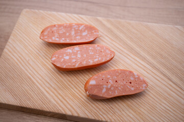 Sliced traditional Czech and Slovak sausages with visible fat pieces on wooden cutting board, close up of spekacky texture, ready for cooking or grilling.