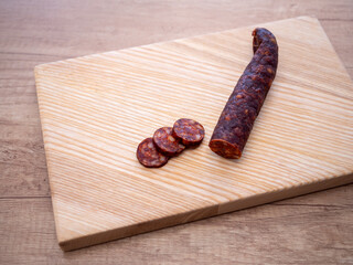 Traditional pork sausage sliced on a wooden cutting board. Smoked homemade delicacy from pig slaughter, typical for Easter and Central European cuisine.
