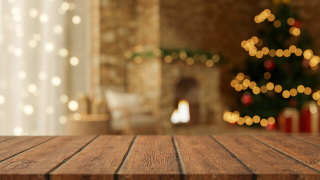 Empty wooden counter table across blurred Christmas tree and lighting fireplace in cosy living room.