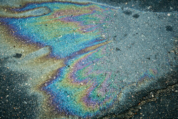 Oil spill creating colorful iridescent rainbow on asphalt