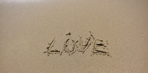 Love word is written on sand top view