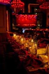 Close-up of a long table with flowers and burning candles in a dark room
