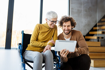 Business woman in wheelchair working with colleague in modern inclusive office. Diversity, support