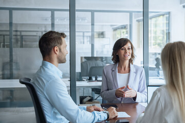 Fototapeta premium Meeting of professional business people working discussing financial trade strategy. Mature female mentor leader Latin woman collaborating with European young team talking about marketing in office.