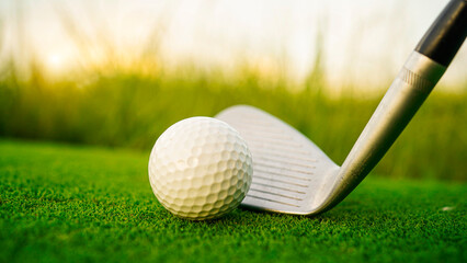 Golf clubs and balls on a green lawn in a beautiful golf course with morning sunshine.