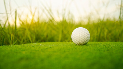 Golf clubs and balls on a green lawn in a beautiful golf course with morning sunshine.