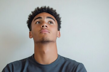 Obraz premium Young man concentrating, looking up with a curious or searching expression. Thinking about prospects, inspiration, or future plans