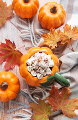 Pumpkin mug of hot chocolate with autumn leaves