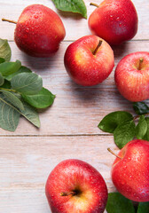 Fresh red gala apples with green leaves and water drops on rustic wooden surface
