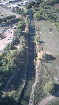 Aerial view of the Cache La Poudre River cutting through the landscape, with trees lining its banks and fields stretching beyond, Greeley, Colorado, United States.