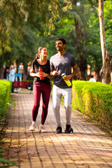 Obraz premium Indian young couple jogging in park enjoying morning fitness, outdoor freshness and bonding