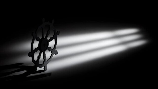 Buddhist dharmachakra wheel silhouette in three frames with moving light beams and shadow on a dark backdrop, video footage