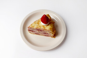 A slice of crepe cake topped with strawberries