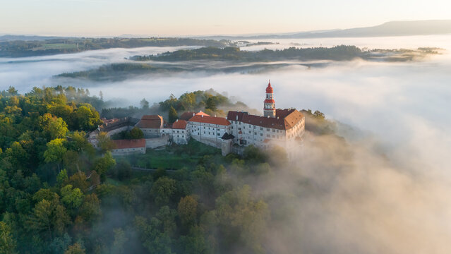 N&aacute;chod Castle at sunrise with fog in the valley engulfing the entire town of N&aacute;chod. Aerial view. Sunny summer or autumn day, Czech Republic