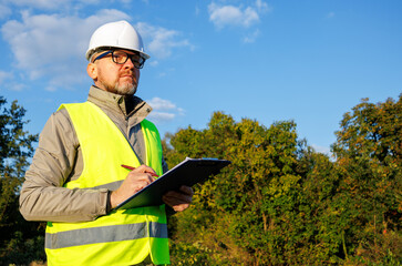 Male engineer inspects the condition of a new construction site. Work forestry inspector, environmental control. Ecologist conducts environmental monitoring soil analysis. 