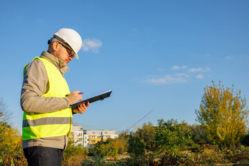Male engineer inspects the condition of a new construction site. Work forestry inspector, environmental control. Ecologist conducts environmental monitoring soil analysis. 