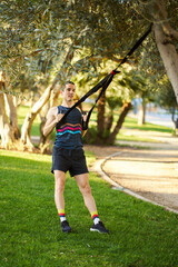 Man training with suspension straps in park