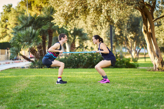 Couple doing partner resistance band workout in park