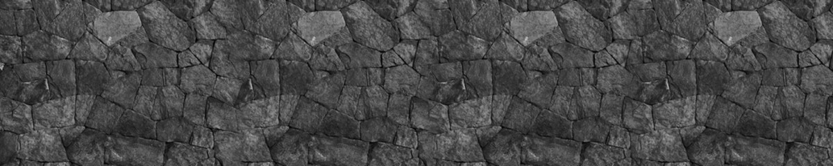 Close up textured abstract background of rough dark black tacked stones.