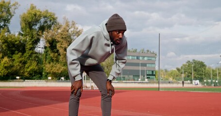 African american man having a break on running track during autumn jogging - Powered by Adobe