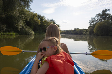 Mother and daughter kayaking on calm river on a sunny summer day, enjoying outdoor adventure and family time together in nature