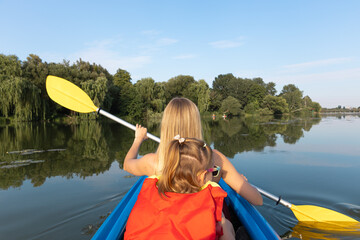 Mother and daughter kayaking on calm river on a sunny summer day, enjoying outdoor adventure and family time together in nature
