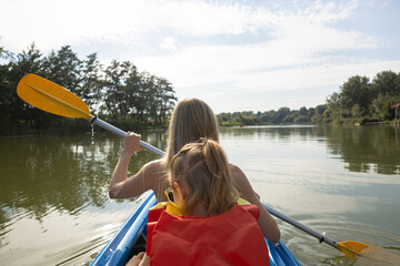 Mother and daughter kayaking on calm river on a sunny summer day, enjoying outdoor adventure and family time together in nature