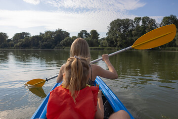 Mother and daughter kayaking on calm river on a sunny summer day, enjoying outdoor adventure and family time together in nature